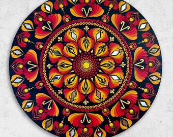 Puede incluir: Un mandala circular pintado sobre un fondo negro con un esquema de colores rojo, naranja y amarillo. El mandala presenta un diseño floral central con detalles intrincados y un patrón repetitivo de pétalos.
