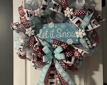 May include: A winter wreath with a "Let it Snow" sign. The wreath features silver mesh, red and white polka dot ribbons, and light blue ribbons with snowflake and top hat patterns. White snowflake ornaments are also included.