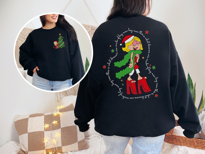 May include: Black sweatshirt with a Christmas-themed graphic of a woman wearing a red Santa hat and green scarf, standing on high heels. The text around the graphic reads "This is what dreams are made of, fly now, hey now, this is what dreams are made of, fly now, hey now".