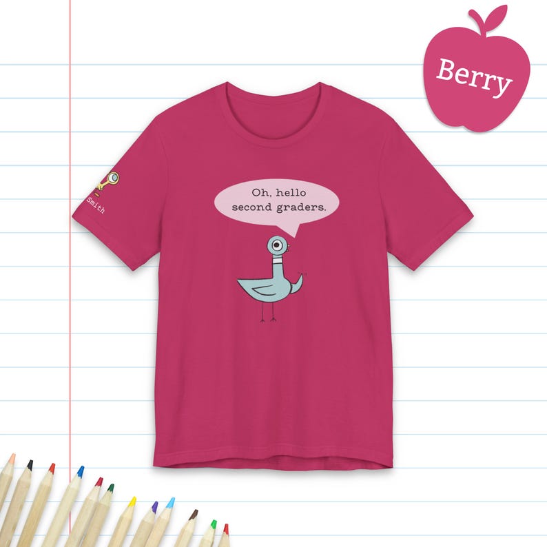May include: A berry-colored short-sleeve t-shirt featuring a graphic of a light blue pigeon with a speech bubble that says, Oh, hello second graders. The sleeve includes a small magnifying glass icon and the text Smith.