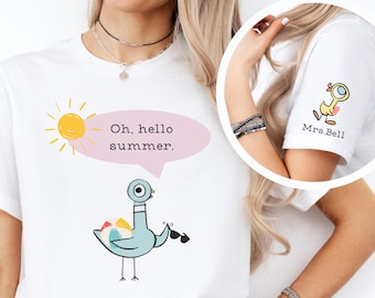 May include: White t-shirt with a blue bird holding a beach ball and sunglasses. The shirt has a pink speech bubble with the text "Oh, hello summer." and a yellow sun with rays.