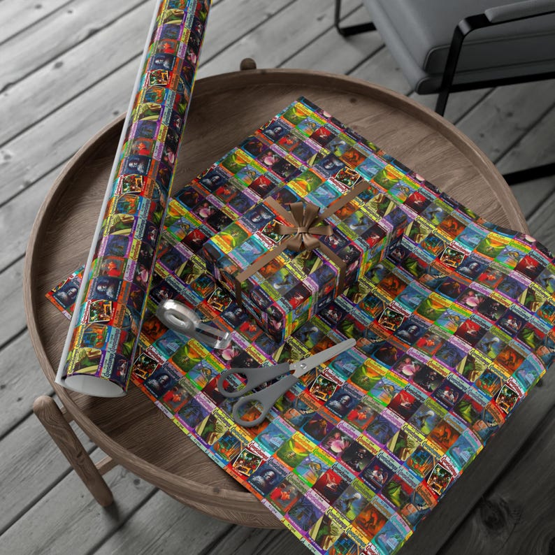 May include: A brown wooden tray with a colorful wrapping paper featuring a repeating pattern of vintage book covers. A small gift box wrapped in the same paper is on the tray. A roll of wrapping paper is also on the tray.