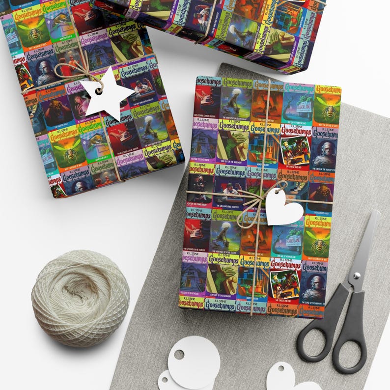 May include: Two rolls of wrapping paper with a colorful pattern of Goosebumps book covers. The paper is wrapped around gifts and tied with twine. There are also gift tags and scissors on the table.