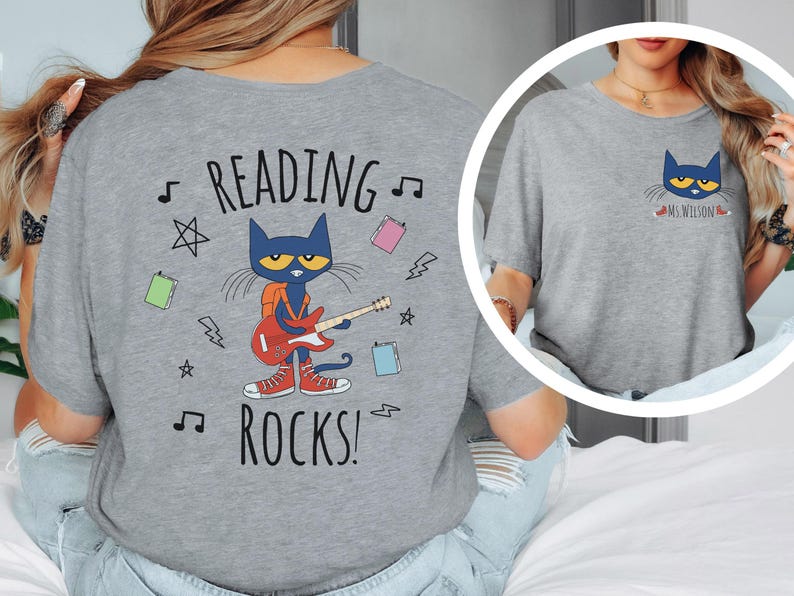 May include: Gray t-shirt with a blue cat character playing a guitar and the text "Reading Rocks!" on the back. The front of the shirt has a smaller image of the cat with the text "Ms. Wilson".