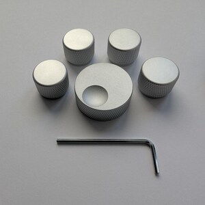 Peut inclure: Ensemble de cinq boutons de commande argent&eacute;s avec une surface textur&eacute;e, dispos&eacute;s autour d'un bouton plus grand avec une d&eacute;coupe circulaire. Une cl&eacute; Allen argent&eacute;e est &eacute;galement incluse.