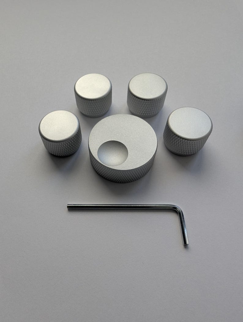 Peut inclure: Ensemble de cinq boutons de commande argent&eacute;s avec une surface textur&eacute;e, dispos&eacute;s autour d'un bouton plus grand avec une d&eacute;coupe circulaire. Une cl&eacute; Allen argent&eacute;e est &eacute;galement incluse.