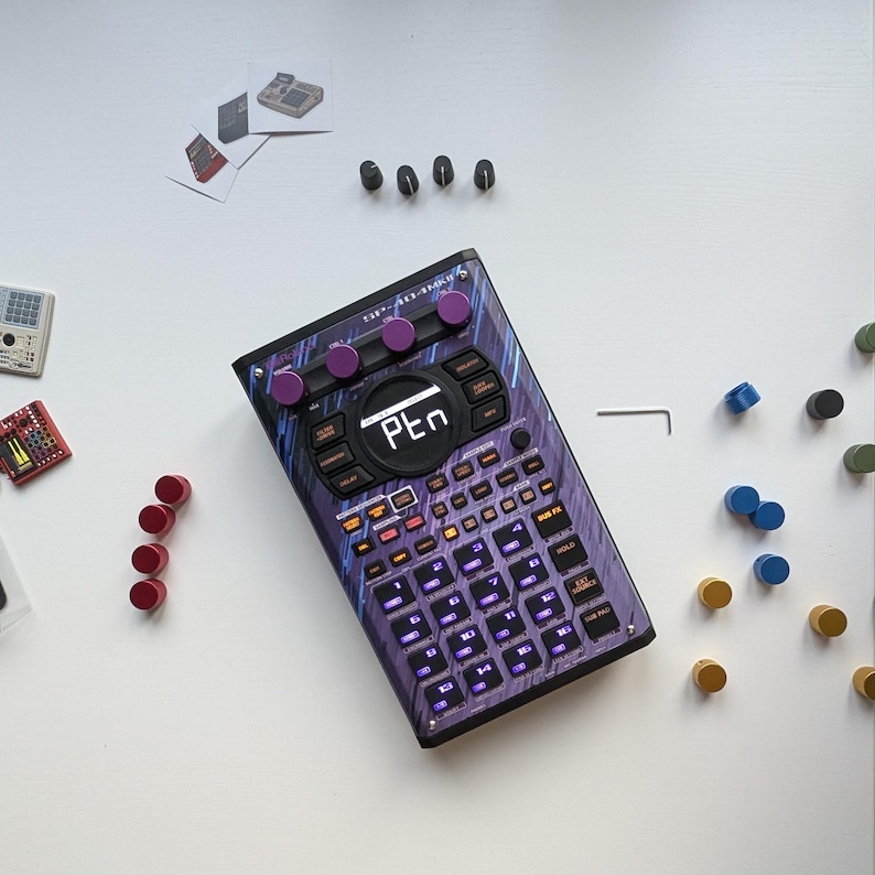 May include: A purple and black SP-404MKII sampler with a digital display showing "PEn". The device has numerous buttons and knobs, with additional red, black, and blue components scattered around it. The device has a unique design with a purple and blue pattern.