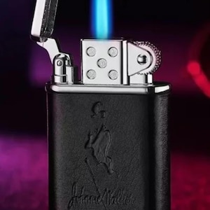 May include: A black and silver lighter with a blue flame. The lighter has a leather-like finish and the words "Johnnie Walker" embossed on the front.