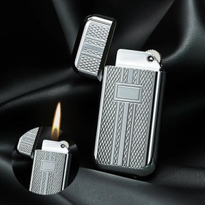 May include: A silver lighter with a textured design and a small flame coming out of the top.