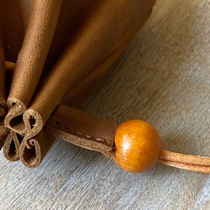 May include: A brown leather pouch with a wooden bead on the drawstring.