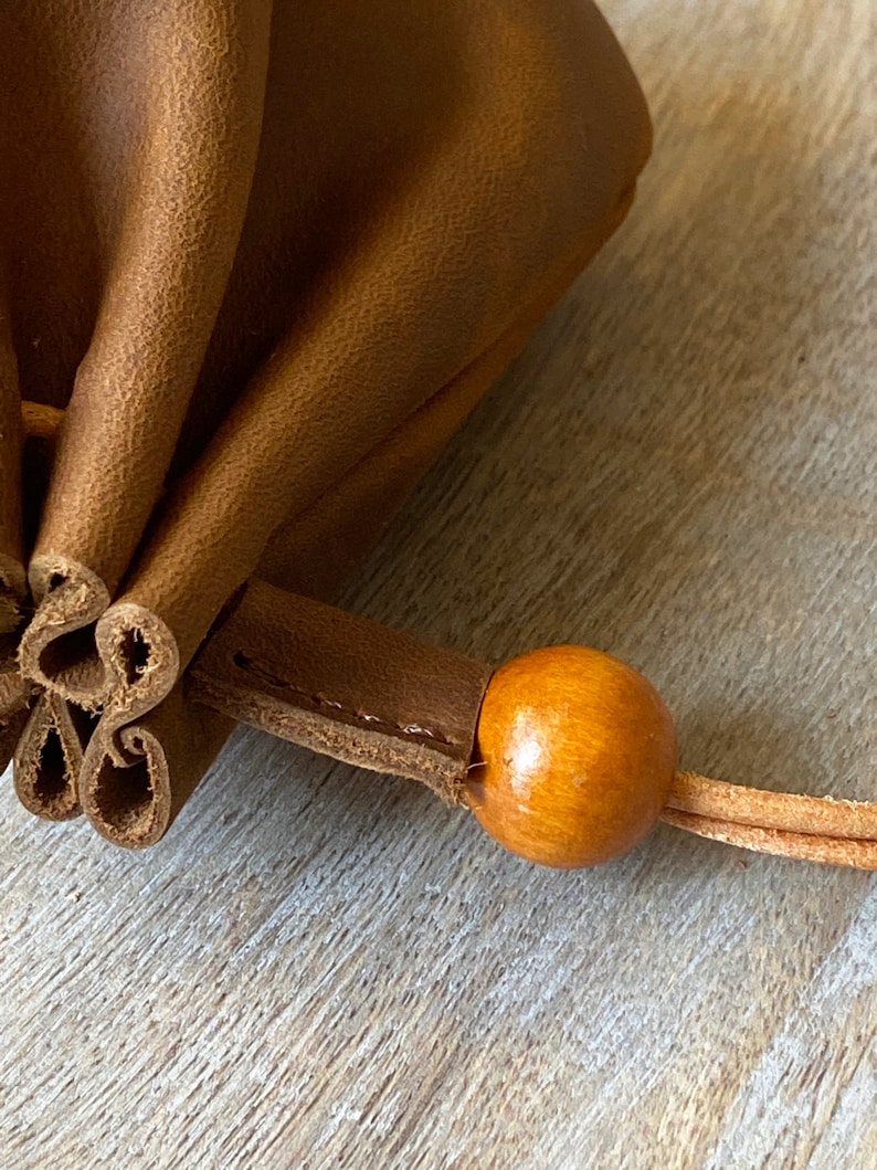 May include: A brown leather pouch with a wooden bead on the drawstring.