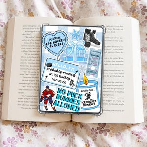 Può includere: Una custodia trasparente per telefono a tema hockey blu e bianco. La custodia presenta vari adesivi, tra cui un cuore con la scritta "Sucker for Hockey Players", un pattino da hockey e il testo "Hello, I'm probably reading an ice hockey romance."