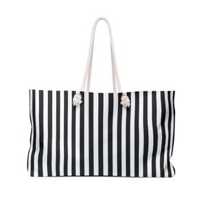 May include: A large tote bag with a black and white vertical stripe pattern. The bag has white rope handles and white accents where the handles attach to the bag. The bag is rectangular and appears to be made of a sturdy material.