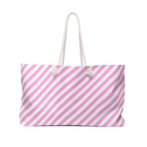 May include: A large tote bag with a pink and white diagonal stripe pattern. The bag has white rope handles and is designed for carrying items. The bag is made of a soft material.