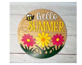 May include: A round wooden sign with the text "hello summer" in white and yellow letters. The sign is decorated with three paper flowers in pink, yellow, and red, and a small bee cutout.