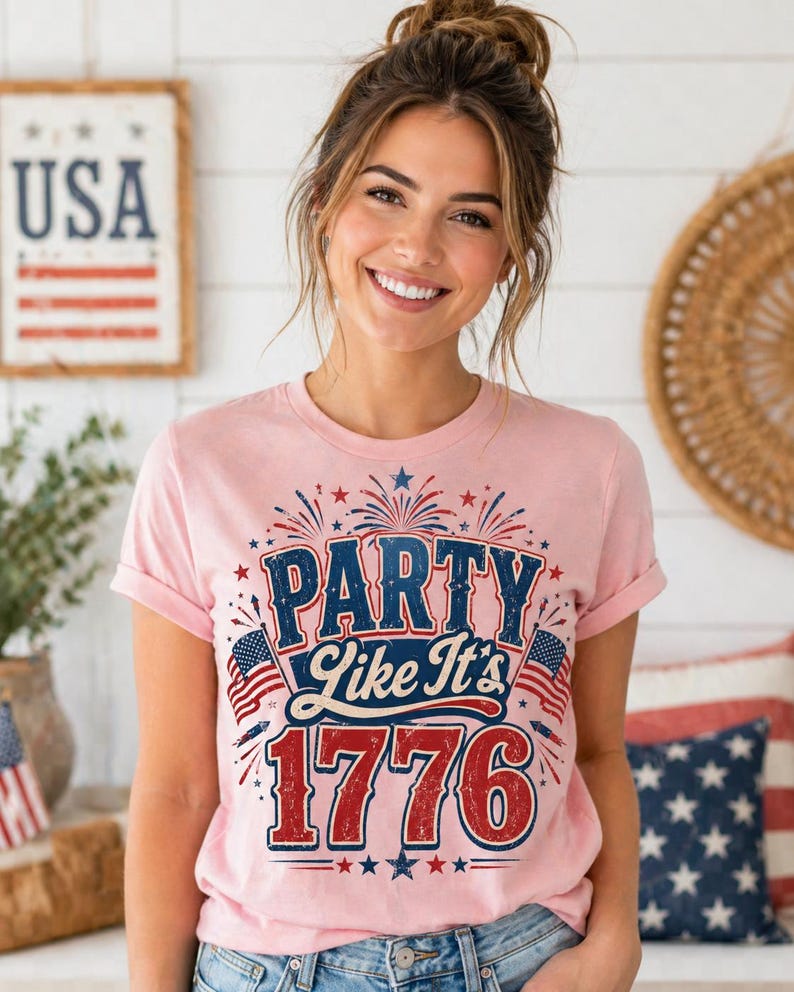 May include: A light pink t-shirt with the text "PARTY Like It's 1776" in blue and red, with fireworks and American flags. The shirt is worn by a person with brown hair.