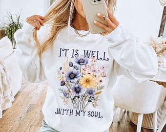 May include: White sweatshirt with a floral design and the text "It is well with my soul".