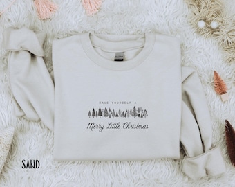 May include: A light beige sweatshirt with a black graphic of a row of trees and the text "Have yourself a Merry Little Christmas".