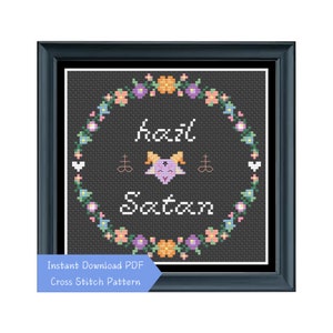 May include: A cross stitch pattern featuring a floral wreath with the text "hail Satan" and a cartoon goat with horns and a halo.
