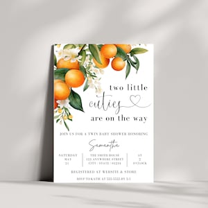 Pu&ograve; includere: Un invito a una festa di baby shower bianco con un design floreale con fiori d'arancio e frutta. Il testo recita "two little cuties are on the way" e include i dettagli dell'evento, tra cui la data, l'ora e il luogo.