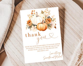 May include: A white card with a watercolor illustration of pumpkins and flowers. The card reads "thank you" in a handwritten style, with additional text below. The card is on a wooden surface.