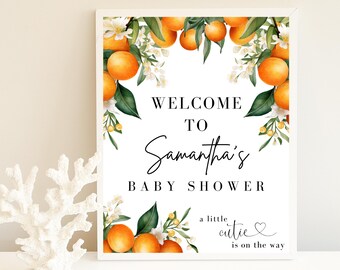 May include: A white sign with orange blossoms and fruit, announcing "Welcome to Samantha's Baby Shower. A little cutie is on the way."