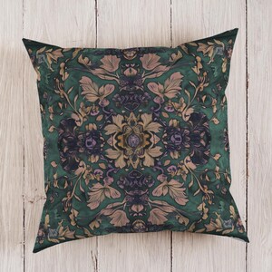 May include: Square decorative pillow with a dark green background and a floral pattern in shades of beige, purple, and gold. The pillow features a symmetrical design with detailed botanical elements.
