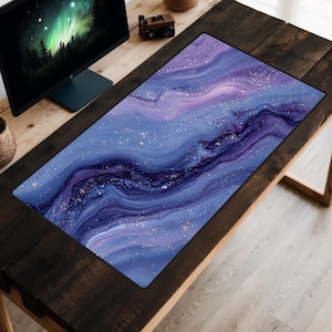May include: A rectangular desk mat with a swirling galaxy design in shades of blue, purple, and white. The mat features a smooth surface and is designed to protect the desk from scratches. The mat is placed on a dark wooden desk.