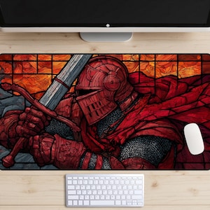May include: A rectangular mouse pad featuring a detailed illustration of a knight in red armor holding a sword. The background has a stained-glass effect with orange and yellow hues. A white mouse and keyboard are visible.