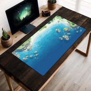 Puede incluir: Una alfombrilla de escritorio azul y verde con una escena de playa. La alfombrilla presenta una playa de arena, agua azul y rocas.
