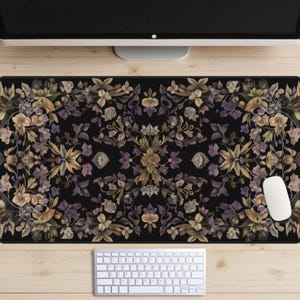 May include: A black desk mat with a floral pattern in shades of brown, purple, and white. The pattern is symmetrical and features intricate details.