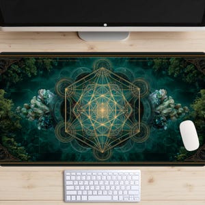 May include: A rectangular mouse mat with a gold and teal geometric design. The design features a central star-like shape, surrounded by circles and lines. The mat has a dark teal background with forest imagery on the sides. A white mouse and keyboard are visible.