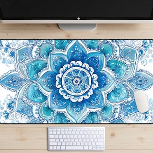 May include: A rectangular mouse pad featuring a large, intricate blue and white mandala design. The floral pattern is detailed with various shades of blue, creating a watercolor effect. A white computer mouse and keyboard are visible.