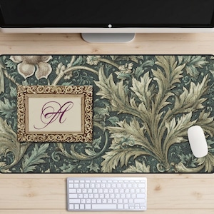 May include: A decorative desk mat featuring a detailed floral pattern in shades of green and beige. A framed rectangle with the letter "A" in a cursive font is on the left. A white mouse and keyboard are also visible.