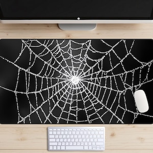 Pode incluir: Tapete de mesa preto com um design de teia de aranha branca. A teia está coberta de gotas de orvalho.