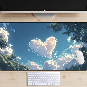 May include: A rectangular mousepad featuring a blue sky with fluffy white clouds forming a heart shape. Green trees frame the sky, with a white mouse and keyboard visible below. The design evokes a serene, natural theme.