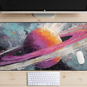May include: A large rectangular desk mat featuring a vibrant abstract painting of a planet with rings. The planet is a mix of orange, purple, and white, set against a backdrop of blues, grays, and black. A white mouse and keyboard are visible.