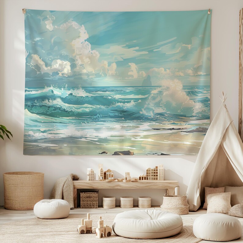 May include: A tapestry featuring a seascape with blue and white waves crashing on a sandy beach. The sky is a light blue with white clouds. The tapestry is hanging on a white wall.