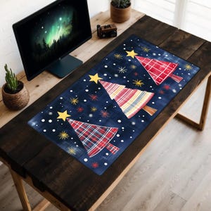 May include: A blue desk mat with a white snowflake pattern and three red, yellow, and blue plaid Christmas trees. The trees are stylized and have a vintage look.