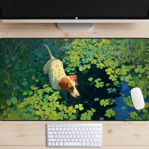 May include: A rectangular desk mat featuring a dog in a pond with lily pads. The dog has brown and white spots and is drinking water. The pond is surrounded by green foliage. A white mouse and keyboard are visible.