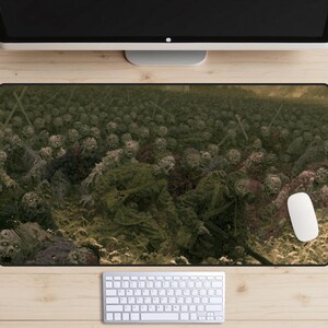 May include: A rectangular desk mat featuring a dark, detailed illustration of a large group of soldiers in military uniforms and gas masks advancing through a field. The scene is rendered in muted earth tones, greens, and browns, depicting a chaotic battlefield.