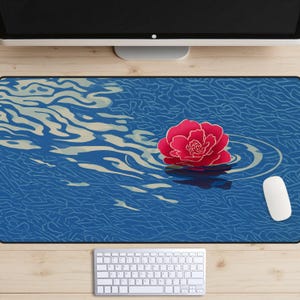 May include: A rectangular mouse pad featuring a stylized illustration of a red flower floating on blue water. The design includes ripples and wave patterns. A white computer mouse and keyboard are also visible.