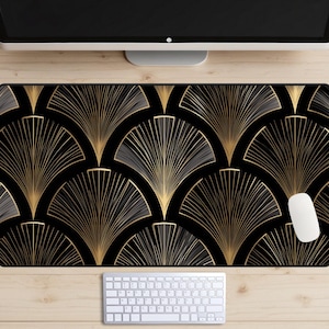 May include: A black and gold Art Deco style desk mat with a repeating fan pattern. The mat is rectangular and features a white computer mouse and keyboard on a wooden desk.