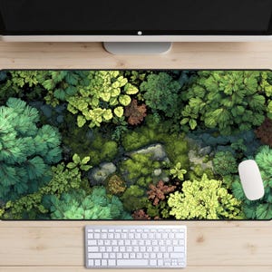 May include: A rectangular desk mat featuring a detailed illustration of a forest scene. The design showcases various shades of green foliage, with hints of brown and gray, creating a naturalistic landscape. A white computer mouse and keyboard are visible.