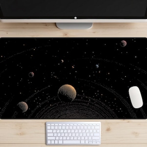 May include: A black desk mat featuring a space-themed design with planets, rings, and stars. The mat has a white mouse and keyboard on a wooden desk. The planets are various colors, including orange, red, and blue.