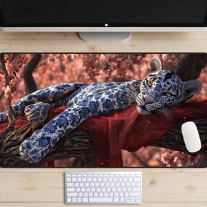 May include: A white and blue patterned leopard is lying on a branch with red fabric underneath. The leopard is surrounded by pink flowers and green leaves.