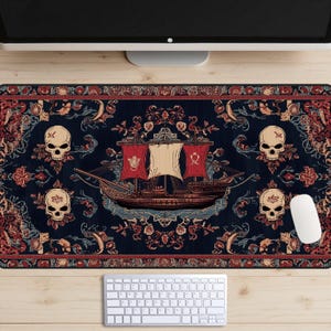 Può includere: Un tappetino da scrivania con motivo blu scuro e rosso con disegni di navi e teschi. Il tappetino presenta una grande nave con vele rosse e un albero maestro bianco. La nave è circondata da teschi con ossa incrociate e motivi floreali.