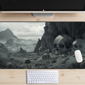 May include: A black and white desktop mouse pad with a dark, foggy landscape and a large skull in the foreground. The landscape features mountains, rocks, and a cave.