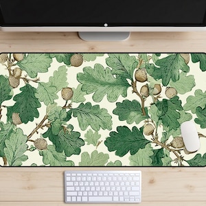 May include: A rectangular mouse mat with a cream background, patterned with green oak leaves and brown acorns. A white computer mouse and keyboard are visible at the bottom of the mat.