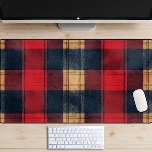 Puede incluir: Una alfombrilla de ratón de cuadros rojos, negros y amarillos con un ratón de ordenador blanco en el lado derecho.